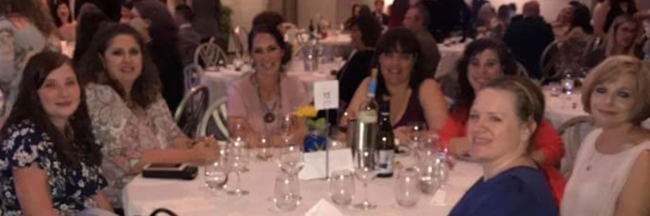 Group of moms sitting around a table, all turned to look at the camera for the picture