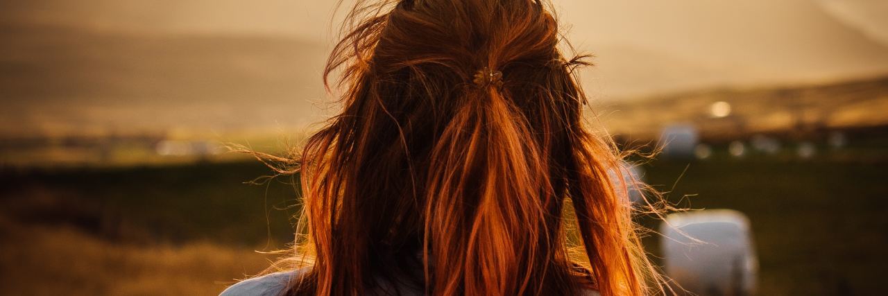 redhead woman watching sunrise over mountains