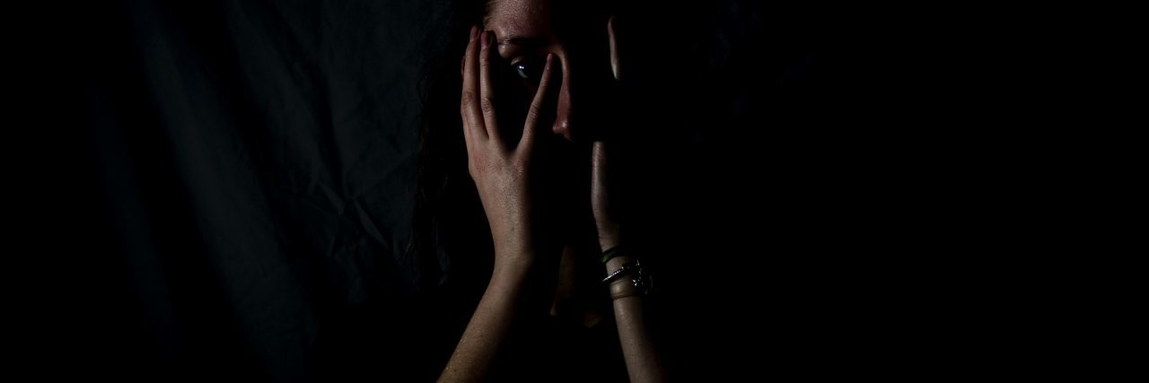 What a Public Panic Attack Feels Like woman in darkness with hands covering her mouth