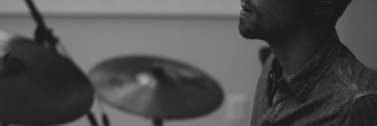 black and white close up photo of man sitting at drum kit