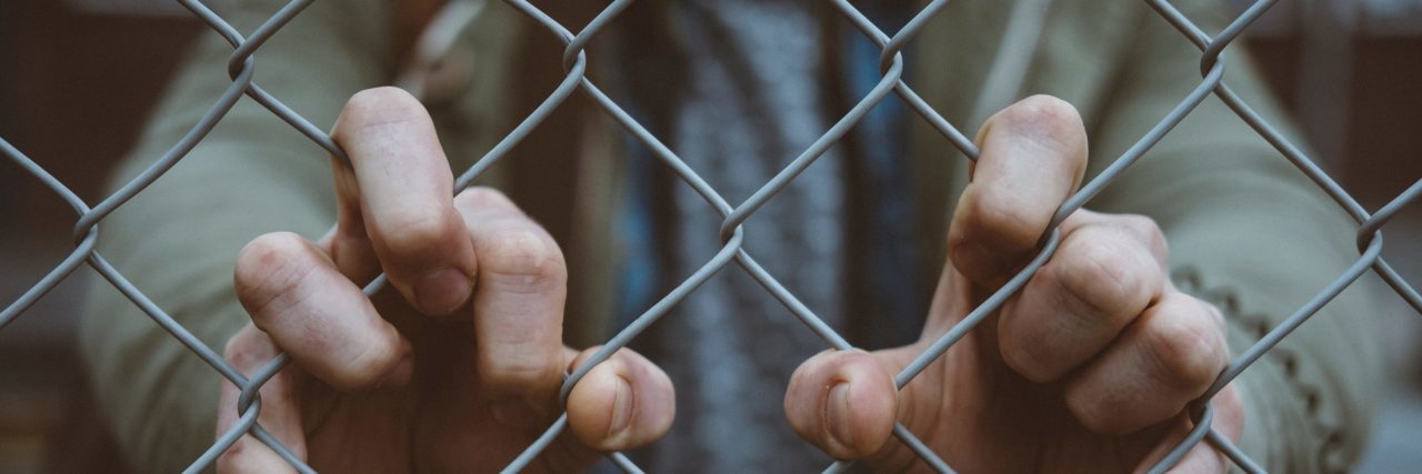 The Barrier Stopping Me From Talking About My Mental Health man grabbing chain link fence close up