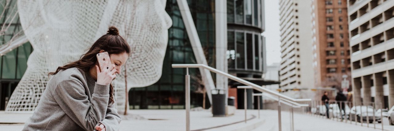 Why You Should Reach out to Others Who Are Struggling With Depression woman on call in city in front of sculpture of giant head