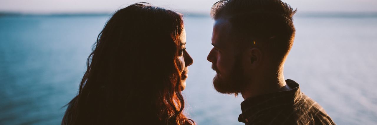 couple looking into each others' eyes in front of ocean