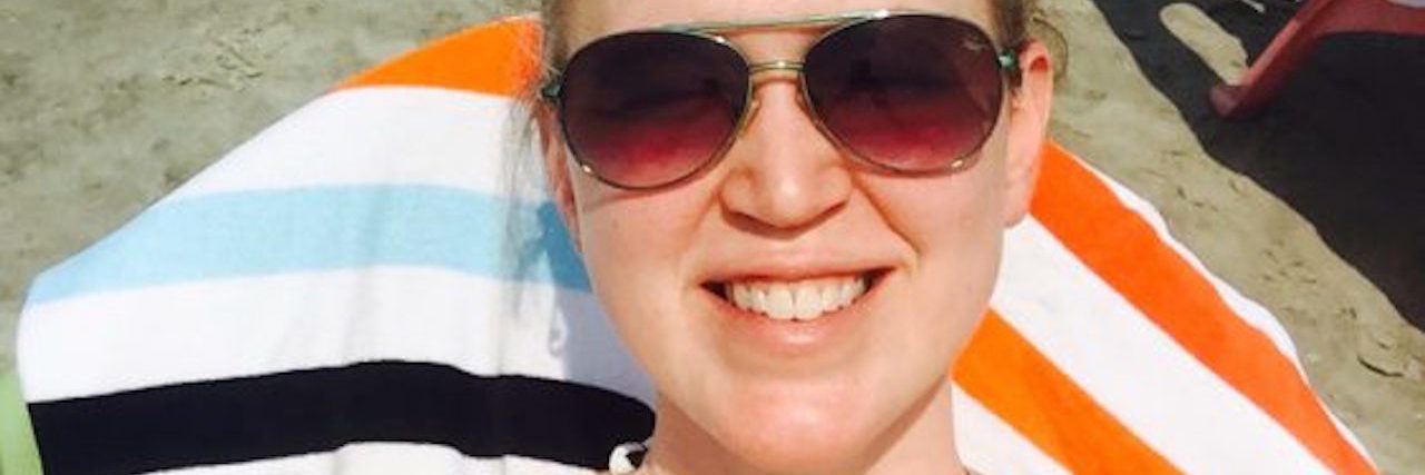 woman lying on beach towel wearing sunglasses