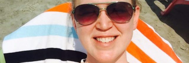 woman lying on beach towel wearing sunglasses