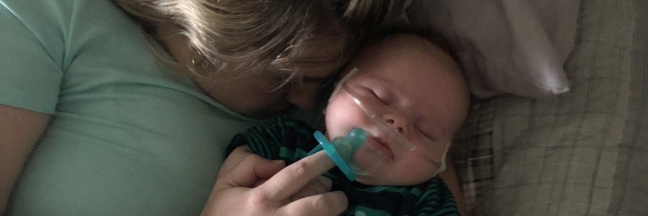 The Highs and Lows of Maternity Leave With My Baby With Down Syndrome Mom snuggling with her baby who sleeps in her arms