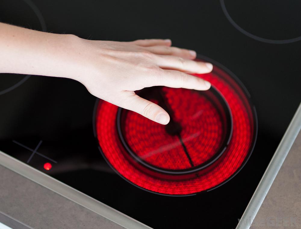 person's hand touching a red hot electric stove