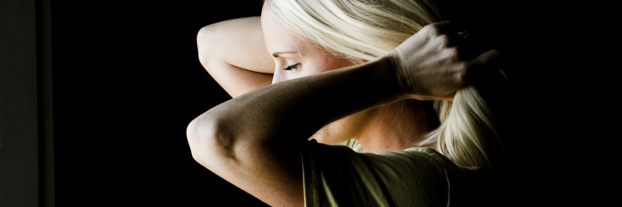 How to Cope With Stress as a PTSD Warrior blonde woman against black backdrop fixing hair