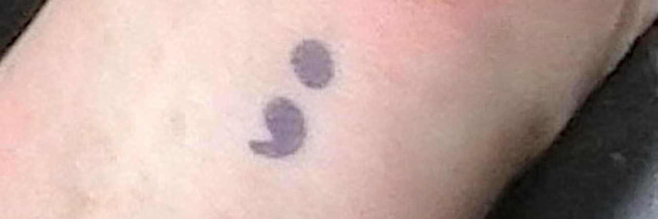 tattoo of semicolon on woman's wrist