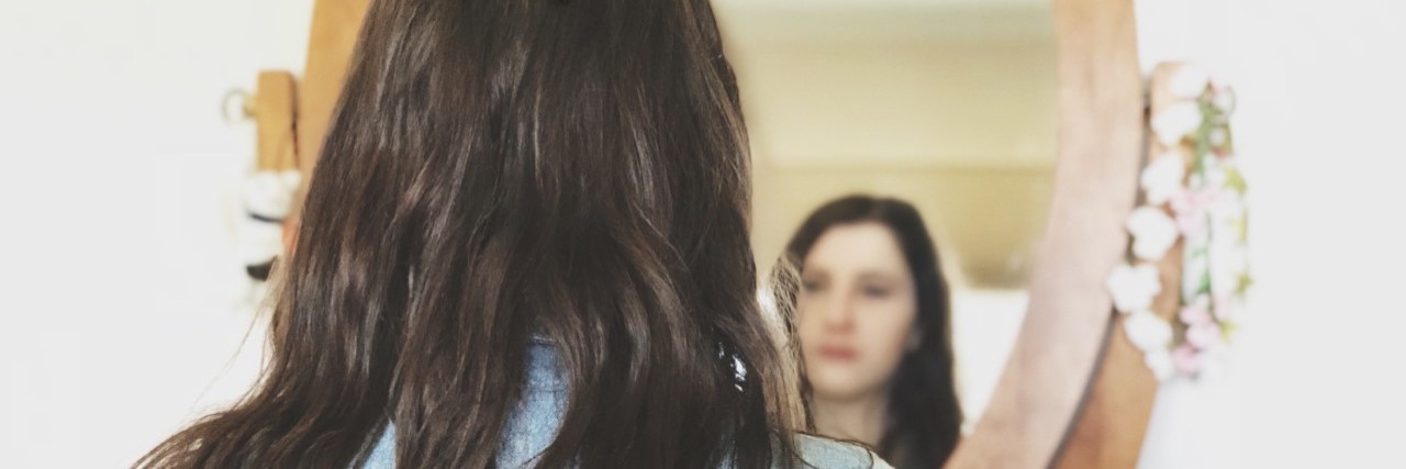 Why Separating Your Illness and Your Identity Can Be So Hard A picture of the write looking at her reflection in the mirror.