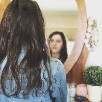 A picture of the write looking at her reflection in the mirror.