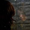 young woman and her reflection in window with brick wall looking sad