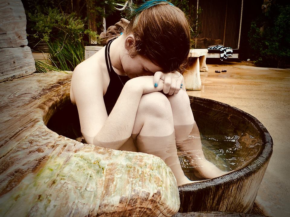 woman curled up sitting in a hot spring