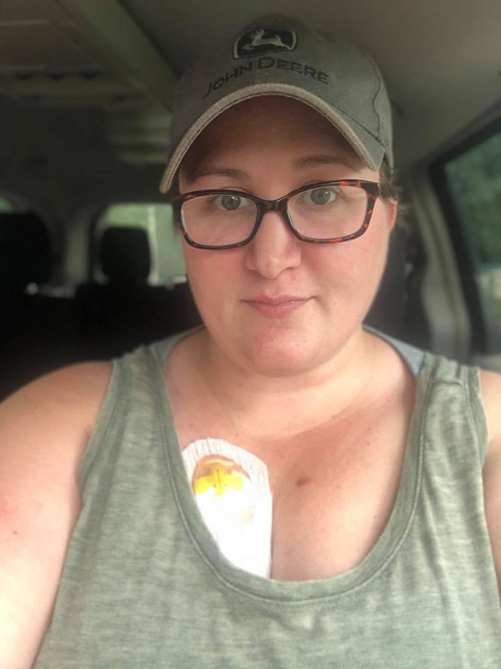 woman taking a selfie wearing tank top and baseball cap