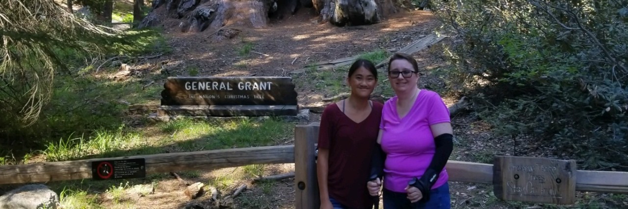 How a Child Encouraged Me When My Illness Prevented Me From Hiking A picture of the writer and her daughter standing ear a big tree in the national forest.