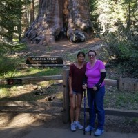 A picture of the writer and her daughter standing ear a big tree in the national forest.