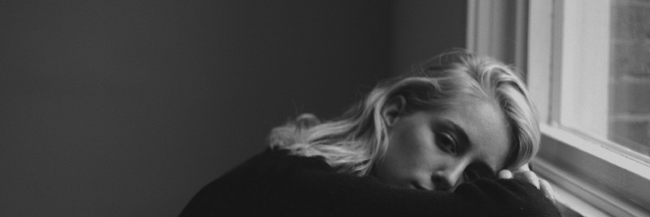 14 Types of Trauma We Don't Talk About A woman with her head on her windowsill. Text reads: 14 Types of Trauma We Don't Talk About