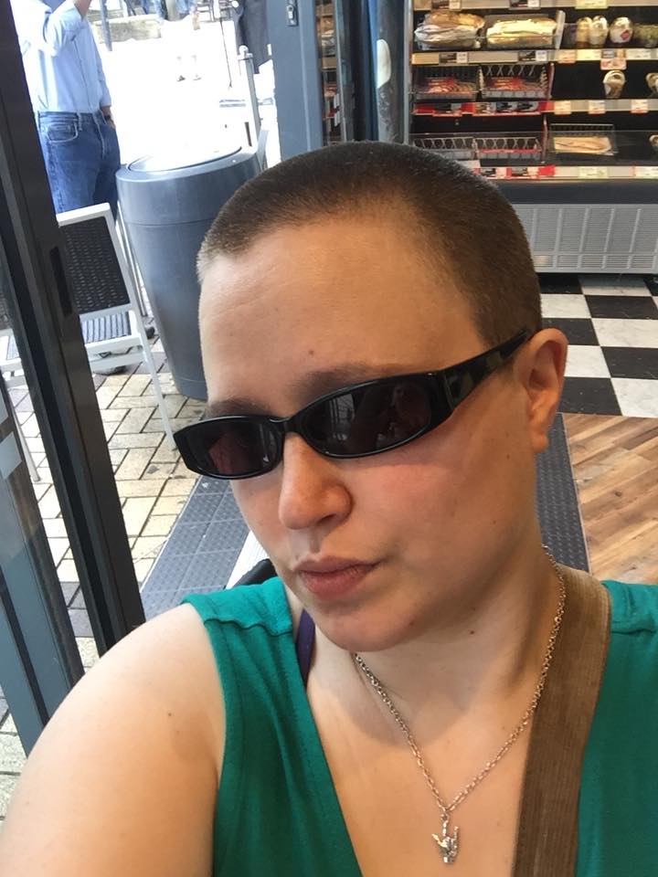a person wearing sunglasses and showing off their shaved head