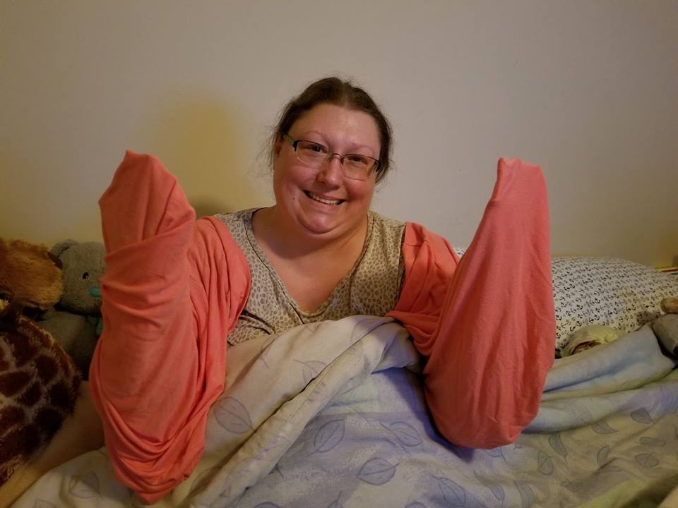 woman with her arms wrapped in soft pink sheets