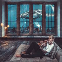 A picture of Avicii playing his guitar on a bed, with a window showing ocean life like a whale – from the perspective of being underwater.