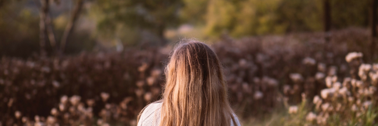 Things People Do That Actually Mean 'I'm Depressed' A woman standing in a filed of flowers. Text reads: 22 Things People Do That Actually Mean 'I'm Depressed'