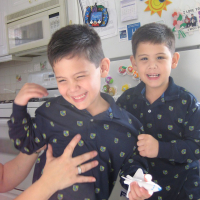 Twin boys wearing matching navy blue pajamas, smiling at camera