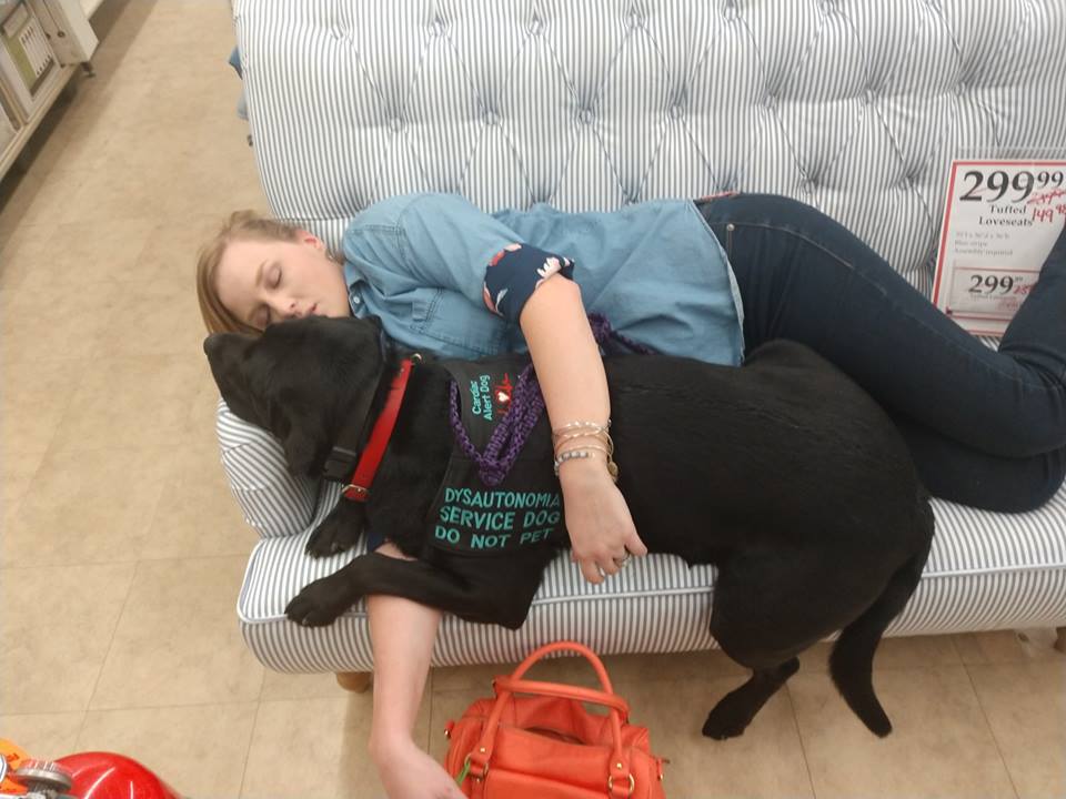 woman sleeping on the couch holding her service dog