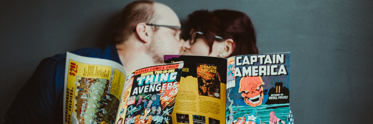 A picture of the writer and her fiancé holding up comics, while kissing.