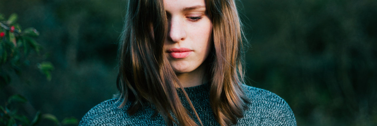 Misconceptions About Borderline Personality Disorder woman in forest area looking down in sadness