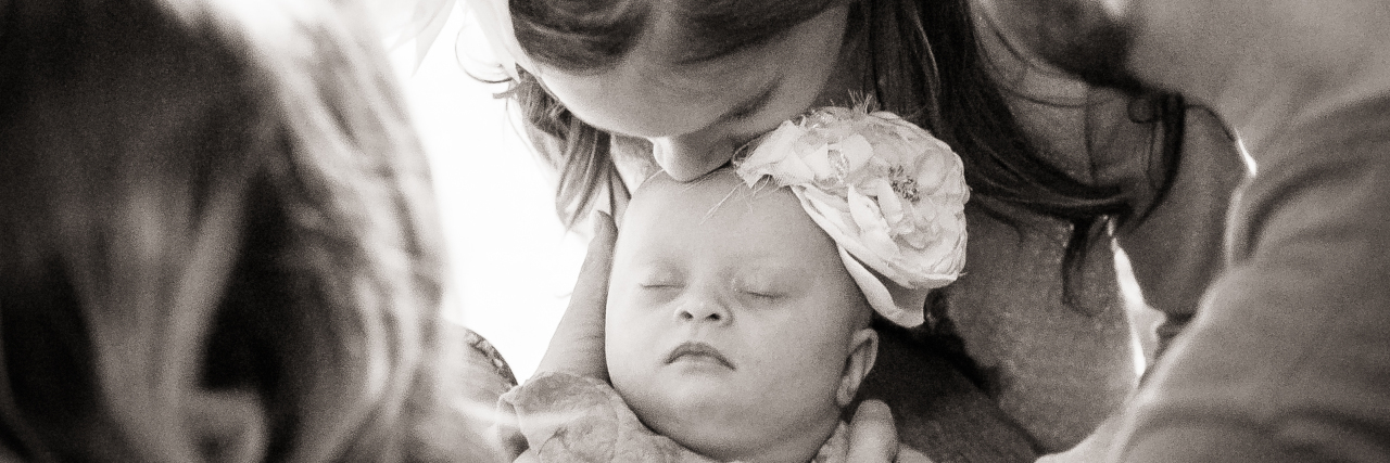 Lies I Told Myself About My Newborn's Down Syndrome Diagnosis Baby with Down syndrome surrounded by mom, dad and older sister. Black and white image.