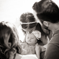 Baby with Down syndrome surrounded by mom, dad and older sister. Black and white image.