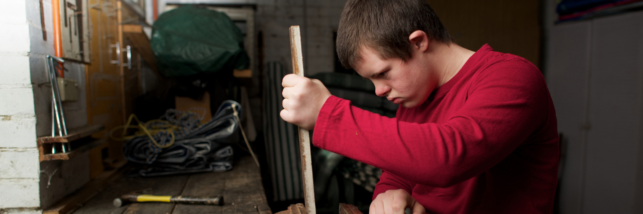Teen with Down syndrome doing woodwork at a shop