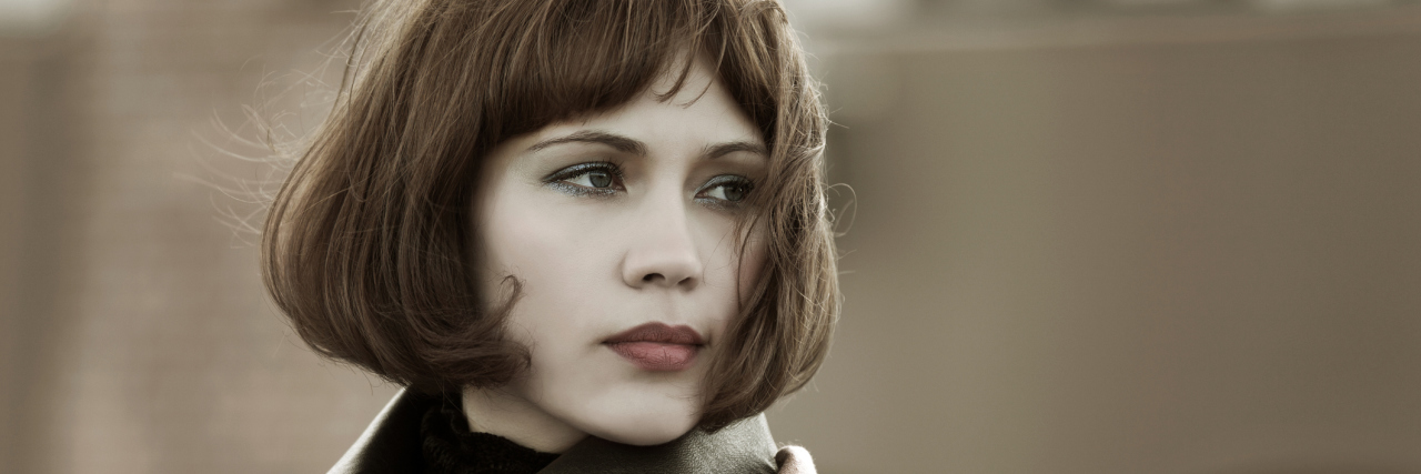 5 Non-Glamorous Symptoms of Hypermobile EDS A woman outside, looking away from the camera.