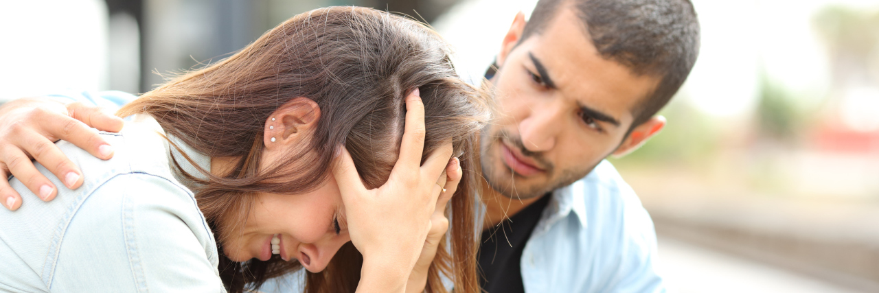 A picture of a woman crying as a man comforts her.