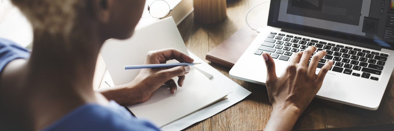 What It's Like Returning to Work With Myalgic Encephalomyelitis A woman working at a laptop.