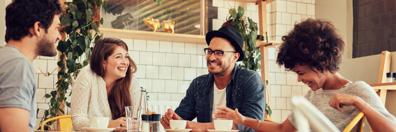 Why It's Helpful to Meet Other People With Chronic Illness in Person group of people sitting around a table talking and laughing