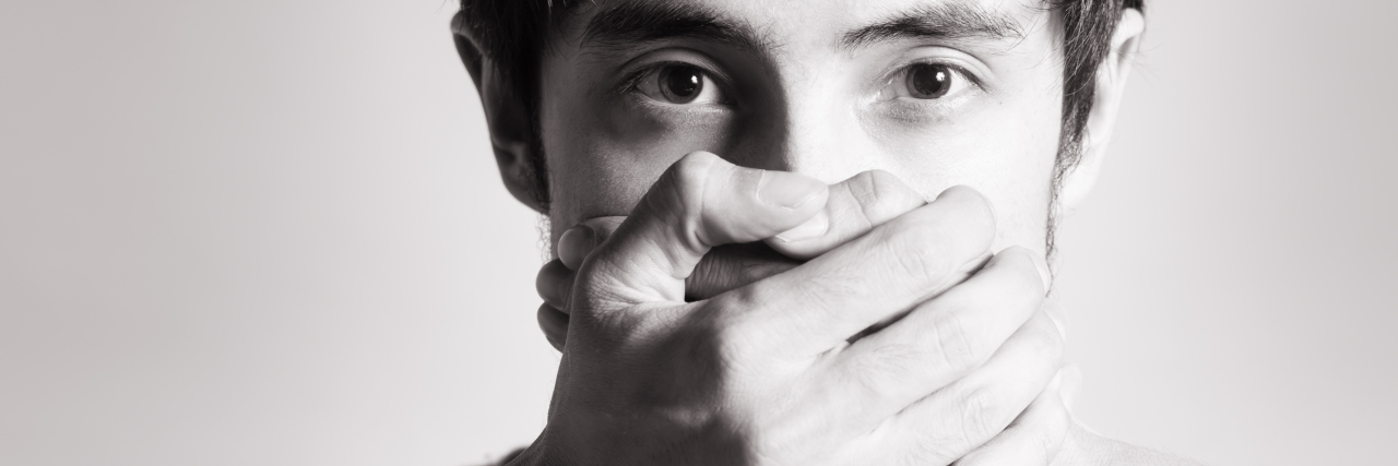 When Anxiety Affects Your Speech Handsome young man with hands covering his mouth.