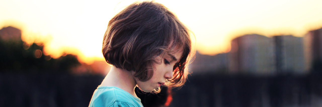 4 Things I Want Kids Growing Up With Arthritis to Know A picture of a young girl looking towards the ground.