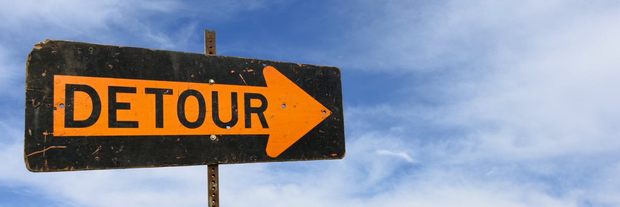 Detour street sign on sky background.