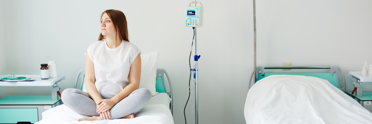 10 Stereotypes People Believe About Women With Chronic Illness Young woman sitting on bed in hospital ward