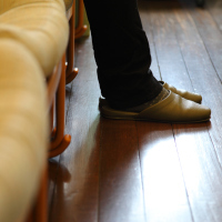 A picture of someone's feet on a wooden floor in a waiting room.