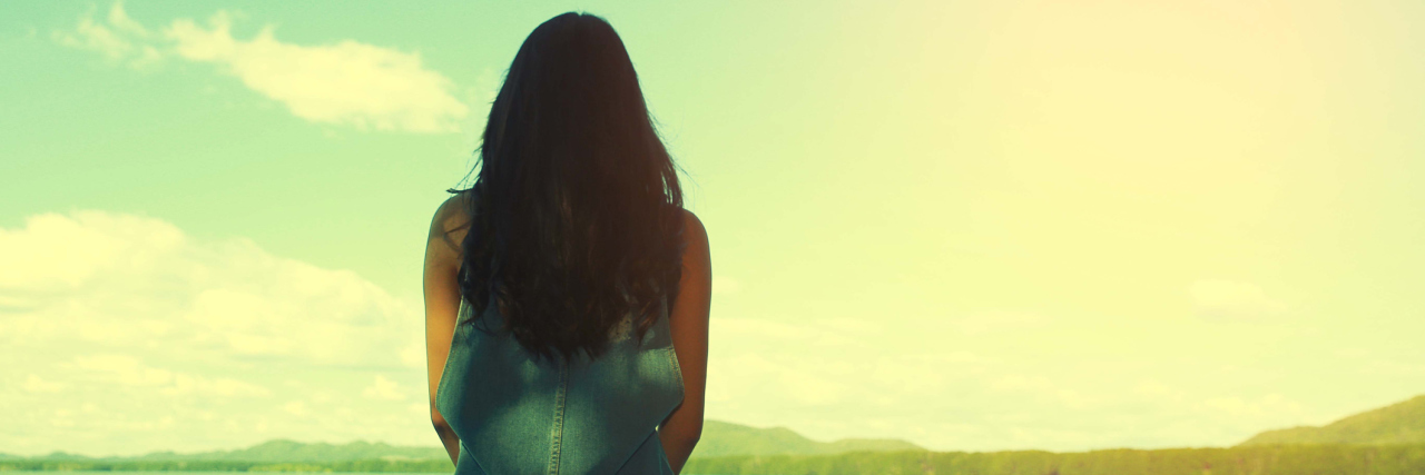 Why I Feel 'Triggered' Now After Past Experiences With Lyme Disease woman sit alone at the edge of the bridge