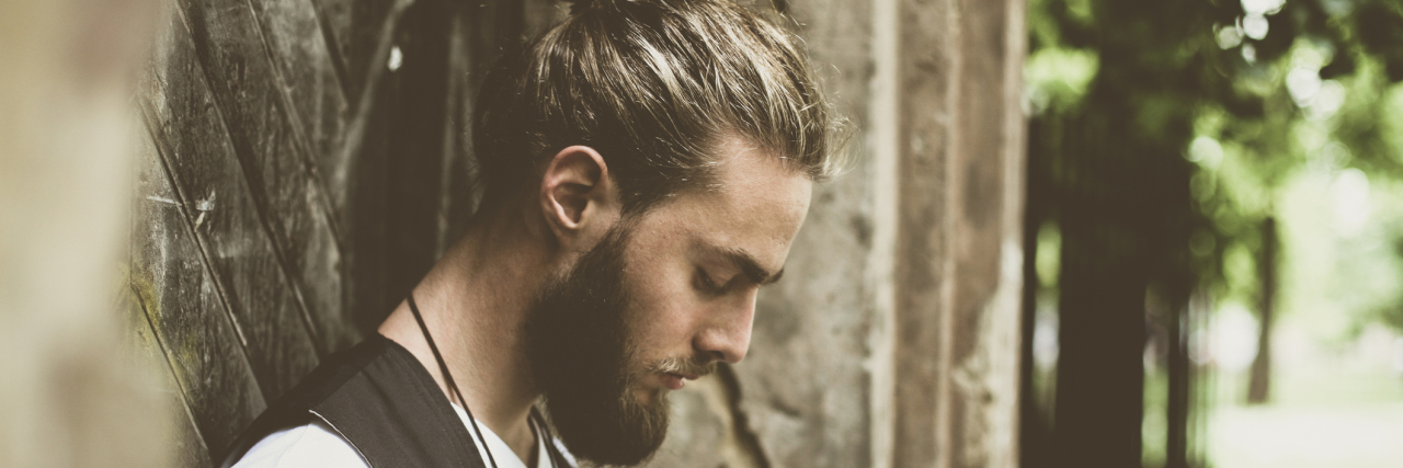 How to Manage Your Thoughts and Emotions Caused by Your Illness A man looking down towards the ground, while standing outside.