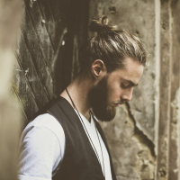 A man looking down towards the ground, while standing outside.