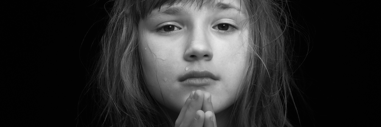 young girl crying. Hands in a gesture of prayer. Black and white portrait