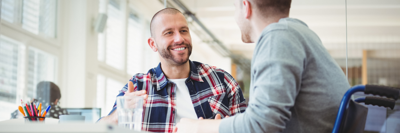 Disability Employment and Merging Departments of Education, Labor Disabled businessman sitting with colleague in office.