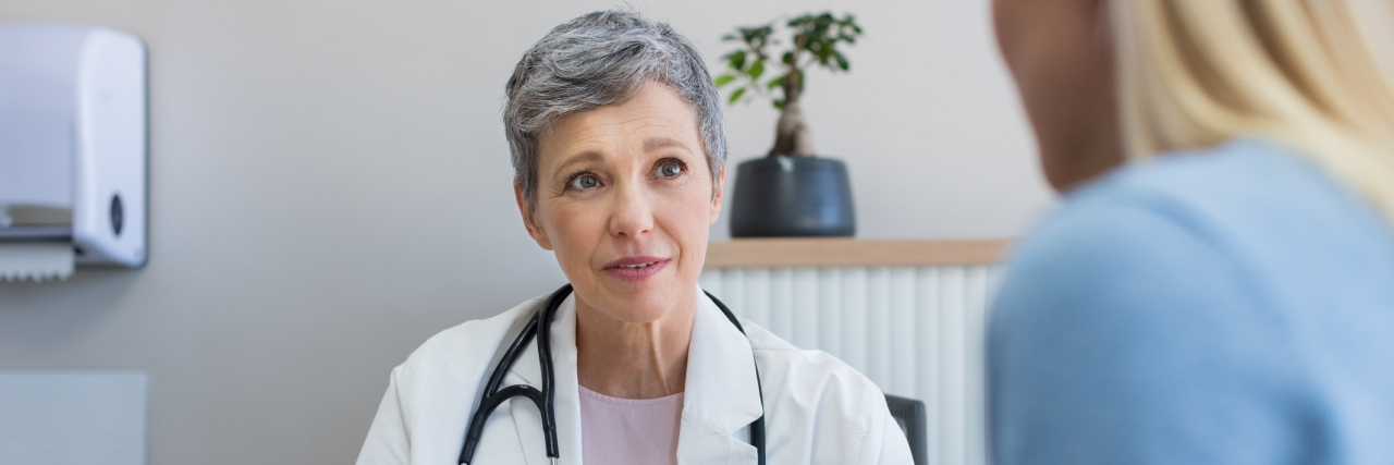 What I Learned When My Doctor Told Me to 'Try to Ignore' My Tinnitus A doctor looking at her patient while taking notes.