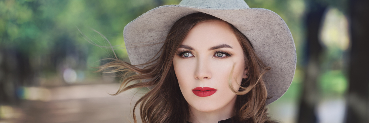 A woman outside, wearing a sun hat.