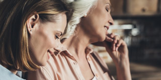 An adult daughter and her mother talking in a kitchen.