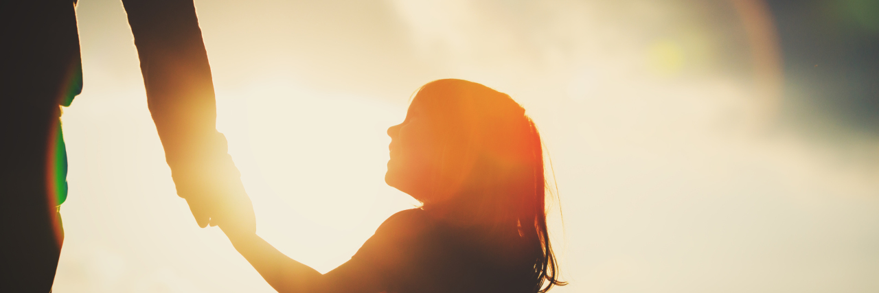 Father's Day as a Daughter With a Disability Silhouette of little girl holding father's hand.